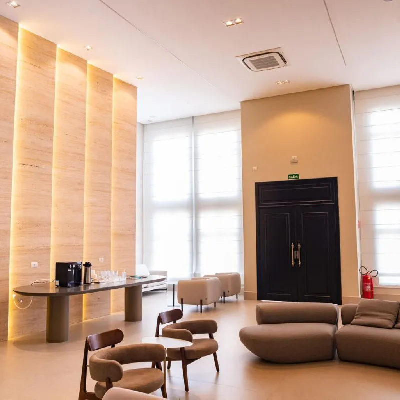 Recepção da Clínica Synergie, com poltronas, mesa de café e painéis de madeira iluminados
