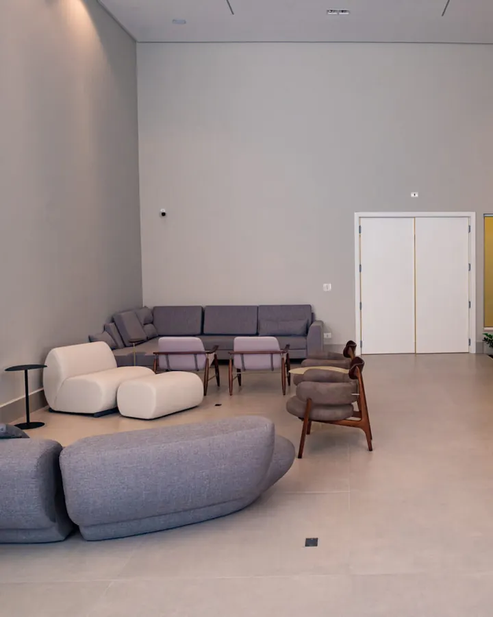 Sala de espera ampla da Clínica Synergie, com sofás cinza e poltronas claras