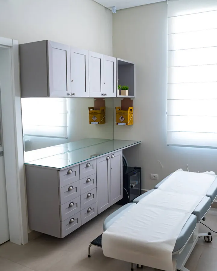 Sala de exame da Clínica Synergie com maca e armários claros